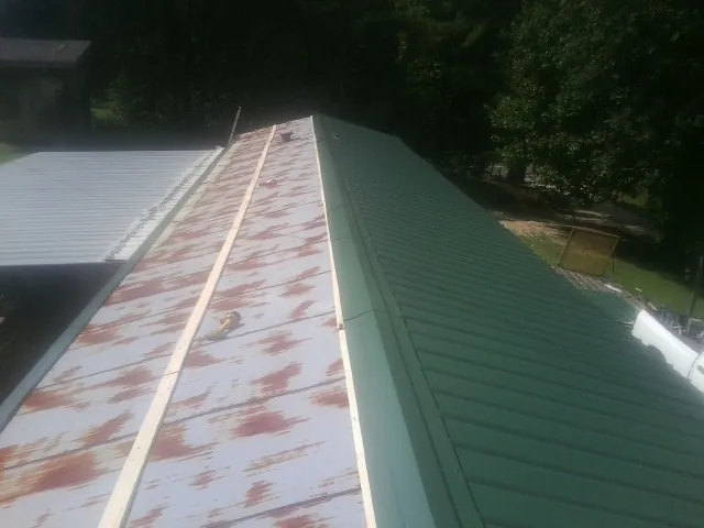 Old rusted panels beside newly installed green metal roofing — Wind Damage Roof Repair by Roofing Brothers in Rocky Hill