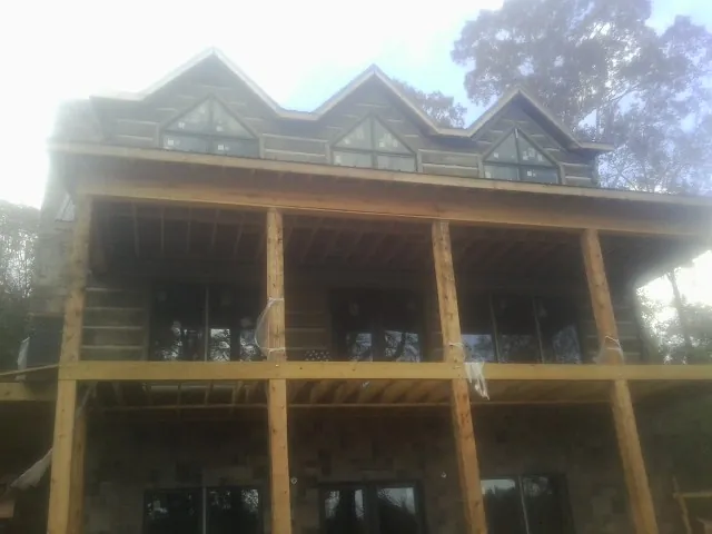 Dormers and porch framing on a large log home under construction — Roof Coating work by our crew in Rocky Hill