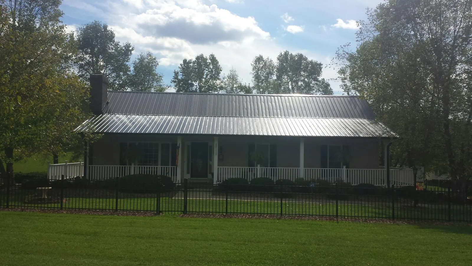 Gray metal roof on a brick ranch with a full width front porch — Gutter Guard Installation work by our crew in Rocky Hill