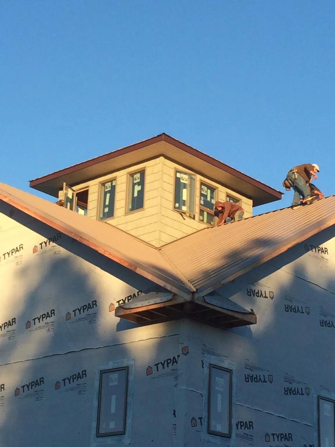 Roofers working around a rooftop cupola on a new metal roof at sunset — Roof Waterproofing in Rocky Hill by Roofing Brothers